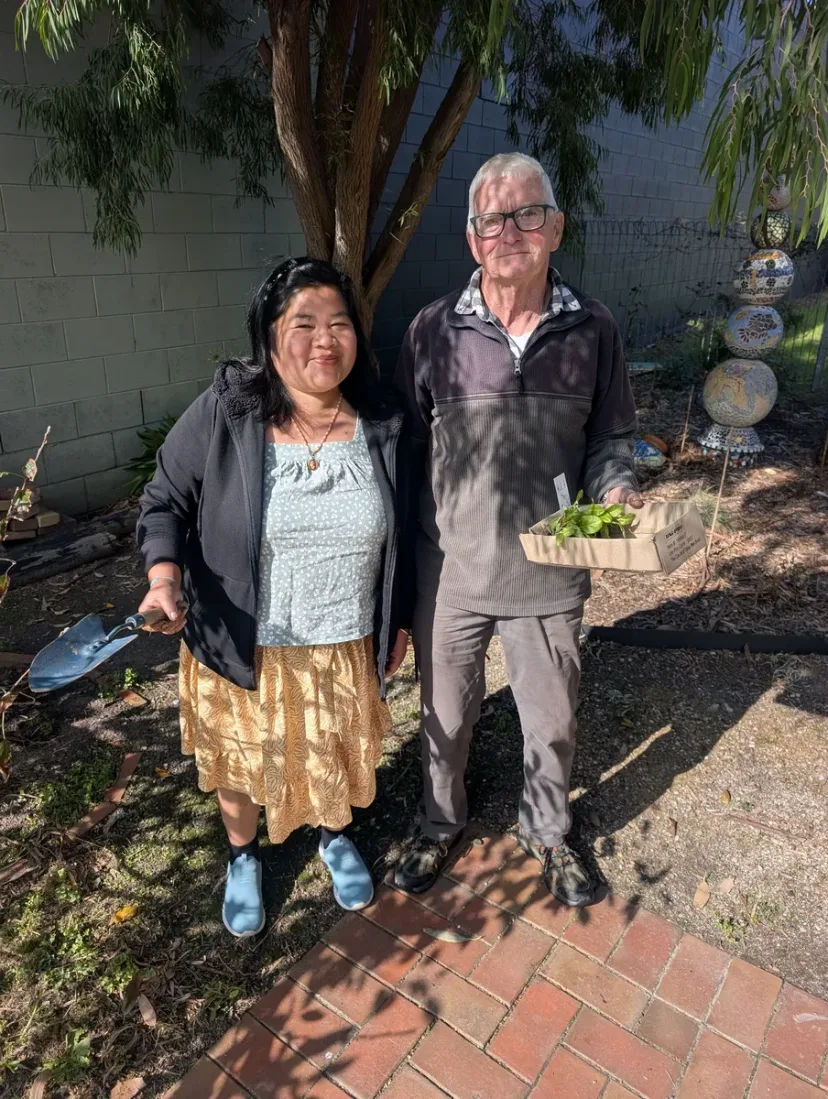 Two people with fresh produce in the community garden